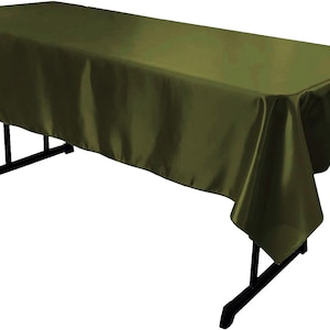 May include: A rectangular olive green tablecloth with a smooth, satin-like finish draped over a black folding table. The fabric covers the top and hangs down over the sides, displaying a consistent dark green color and a subtle sheen across the surface.