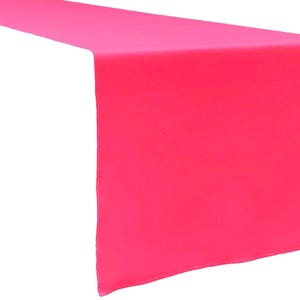 May include: A solid hot pink table runner with a smooth, matte texture. The rectangular fabric piece is draped to show a flat top surface and a vertical side panel, displaying a consistent, vibrant neon pink colour throughout the entire textile.
