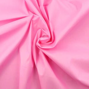 Peut inclure: Un tissu rose bonbon vif et uni présentant une texture lisse et mate. Le matériau est rassemblé au centre, créant des plis profonds et fluides ainsi que des ombres douces qui rayonnent vers l'extérieur, soulignant la couleur rose vive.