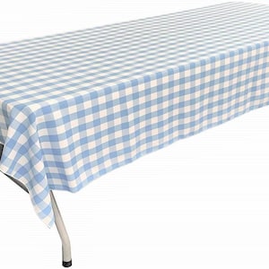 May include: A rectangular folding table covered with a light blue and white checkered tablecloth. The fabric features a consistent gingham pattern that drapes over the edges of the table, which has metal legs and a flat, rectangular surface.