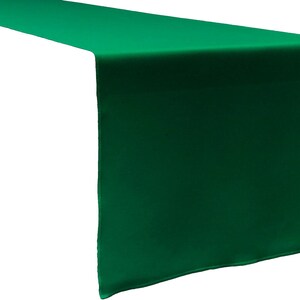 May include: A solid emerald green table runner with a smooth, matte finish. The rectangular textile features clean, straight edges and a consistent, uniform color throughout, designed to drape over the ends of a table surface.