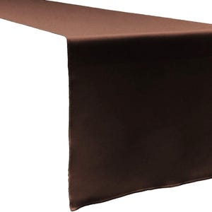 May include: A solid dark brown table runner with a smooth, matte finish and clean, straight edges. The fabric is draped to show a long horizontal section and a vertical drop, highlighting the uniform deep brown color across the entire surface.