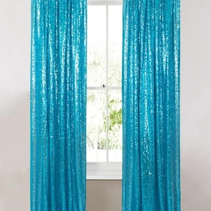 May include: Two floor-length curtains made of bright turquoise fabric covered in shimmering sequins. The curtains are hung on a simple gold-toned metal rod, featuring a rod pocket header that creates vertical folds along the length of the fabric.