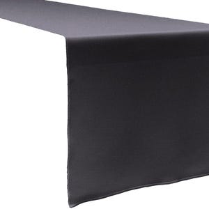 May include: A solid dark grey table runner with a smooth, matte fabric texture. The rectangular textile features clean, straight edges and a consistent, uniform colour throughout, designed to lay flat across a surface with a simple hemmed finish.