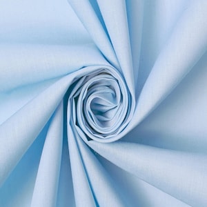 Peut inclure: Un tissu bleu clair à la texture lisse et mate, disposé en une spirale circulaire serrée. Le matériau présente des plis doux et rayonnants qui créent de la profondeur et des ombres, mettant en valeur la couleur unie et uniforme du textile.