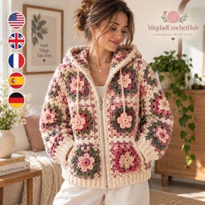 May include: A zip-up hooded jacket crafted from cream, pink, and sage green crochet granny squares featuring floral motifs. The garment includes a front zipper closure, two front pockets, and a ribbed hem and cuffs, showcasing a textured handmade design.