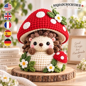 May include: A crochet hedgehog figurine wearing a large red mushroom cap with white spots. The hedgehog has a cream-colored body, brown textured quills, and pink cheeks. It is decorated with small green leaves and white flowers with yellow centers.