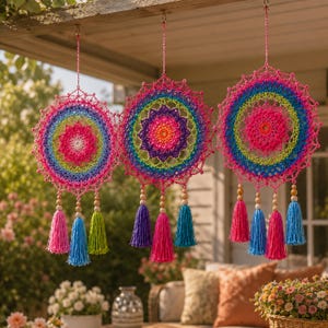 Puede incluir: Tres tapices circulares de ganchillo con patrones de hilo en colores arcoíris vibrantes en círculos concéntricos. Cada pieza está suspendida por un cordón rosa y adornada con cuentas de madera y varias borlas de hilo de colores colgando.