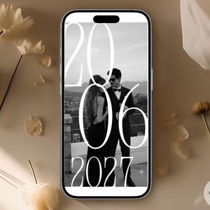 Puede incluir: Un tel&eacute;fono inteligente que muestra una fotograf&iacute;a en blanco y negro de dos personas con vestimenta formal de pie al aire libre. Un texto grande en blanco se superpone a la imagen, mostrando los n&uacute;meros 20, 06 y 2027 en una fuente serif alta.