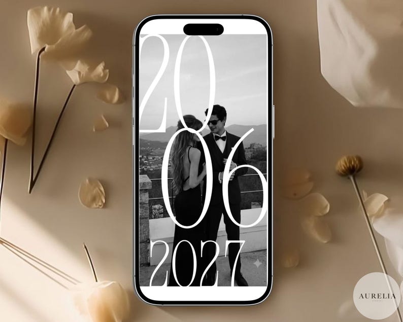 Puede incluir: Un tel&eacute;fono inteligente que muestra una fotograf&iacute;a en blanco y negro de dos personas con vestimenta formal de pie al aire libre. Un texto grande en blanco se superpone a la imagen, mostrando los n&uacute;meros 20, 06 y 2027 en una fuente serif alta.