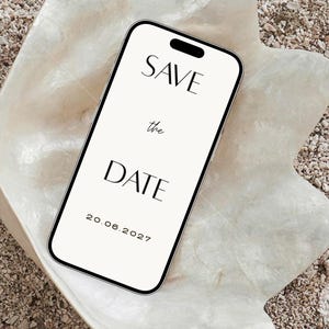 Puede incluir: Un tel&eacute;fono inteligente que muestra un anuncio digital de save the date en blanco con texto negro que dice SAVE the DATE y la fecha 20.06.2027. El dispositivo est&aacute; colocado dentro de una concha grande, iridiscente y blanquecina con interior nacarado.