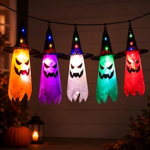 May include: A string of five hanging ghost decorations, each wearing a black witch hat with colorful LED lights. The ghosts are illuminated in orange, purple, white, green, and red, featuring black printed jack-o'-lantern faces with jagged teeth.