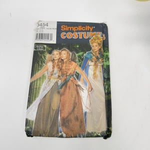May include: A Simplicity Costumes sewing pattern envelope, number 9454, featuring illustrations of three long gowns with draped fabric, capes, and wings. The packaging includes the brand name, the designer Andrea Schewe, and size range 14, 16, 18, 20.