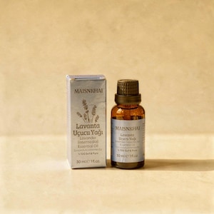Puede incluir: Un frasco de 30 ml de aceite esencial de lavanda MAISNKHAI Lavanta Uçucu Yağı de vidrio marrón oscuro con tapa negra, acompañado de su caja de cartón plateada a juego con una ilustración de una rama de lavanda y la etiqueta 1 fl. oz.