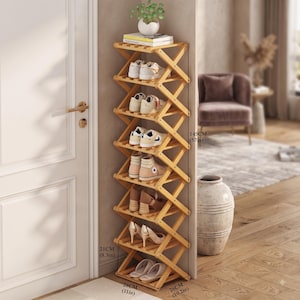 May include: A tall, light-colored wooden accordion-style shoe rack with seven shelves. It measures 145 cm (57 in) high, 28 cm (11 in) wide, and 26 cm (10.2 in) deep, with a 21 cm (8.3 in) base. It holds various pairs of shoes and a small plant.