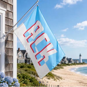 May include: A rectangular flag mounted on a silver pole, featuring a split diagonal design of light blue and white. The letters ACK are printed in a bold, white sans-serif font with a red outline, positioned centrally across the blue and white background.