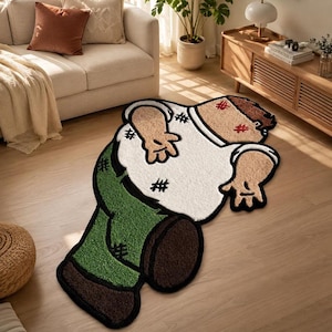 Può includere: Un tappeto tufted a forma di personaggio dei cartoni animati sdraiato a pancia in giù. Il personaggio ha capelli castani, pelle abbronzata, una camicia bianca con dettagli a punto croce neri, pantaloni verdi e scarpe marrone scuro.