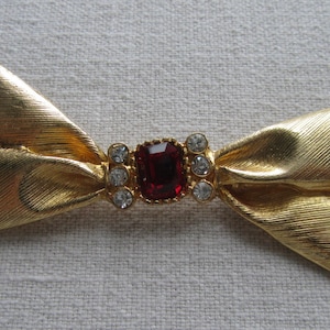 Vintage gold tone oversize bow brooch with red rhinestones