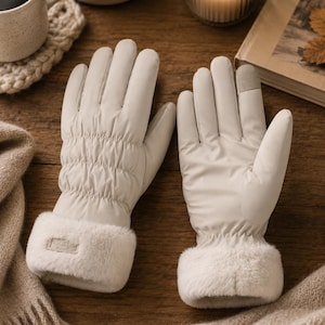 May include: A pair of off-white winter gloves featuring a smooth, quilted back design, a soft faux fur cuff, and a contrasting grey touch-screen compatible fingertip on the index finger. The gloves have a structured shape and a clean finish.