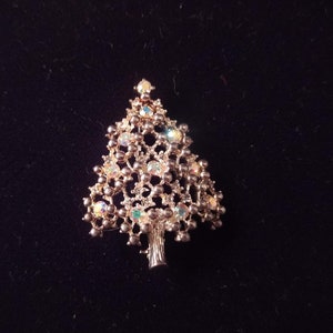 May include: A gold-tone Christmas tree brooch with iridescent rhinestones and a beaded design.