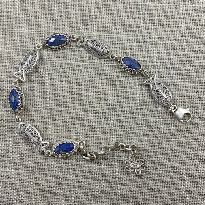 May include: A silver bracelet with blue gemstone fish charms. The bracelet has a filigree design and a lobster claw clasp.