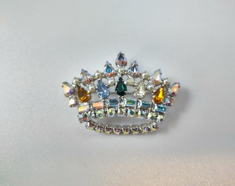 Spilla corona realizzata da B David, metallo tono argento, tondo trasparente, strass a goccia e baguette, strass colorati a goccia, perle di semi
