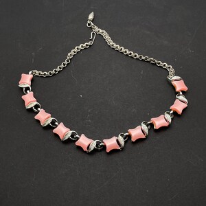 May include: A silver chain necklace with pink, square-shaped stones. The stones have a slightly rounded edge and are set in a silver frame.