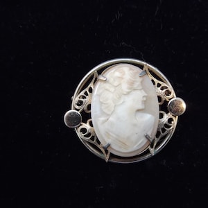 May include: A white ceramic mug with a black handle and the text "But First, Coffee" in a black, bold font. The mug is on a white surface.