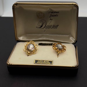 May include: A pair of gold-filled earrings with cameo inlays, in a black velvet box with a white satin lining. The box has a label that reads "Precious Jewels by Donna 1/20-12 KT GOLD FILLED".