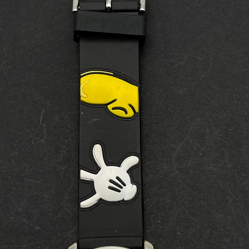 May include: Black watch band with a white and yellow Mickey Mouse glove design.
