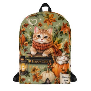 May include: A backpack featuring an autumn-themed print with a ginger kitten wearing a scarf, pumpkins, fall leaves, a lantern, and books labeled "Autumn" and "Happy Cats." A mug is printed with "Pumpkin Spice &" on a sage green background.
