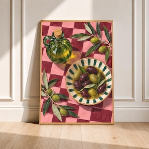 May include: A framed art print featuring a painting of a green glass olive oil cruet with a cork stopper and a striped bowl filled with green and dark purple olives. The objects rest on a pink and dark red checkered surface with olive branches.