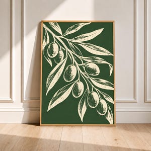 Könnte beinhalten: Ein rechteckiger Wandkunstdruck in einem hellen Holzrahmen mit dunkelgrünem Hintergrund und einer cremefarbenen botanischen Illustration eines Olivenzweigs. Das Design zeigt detaillierte Linienführung von länglichen Blättern und Oliven.