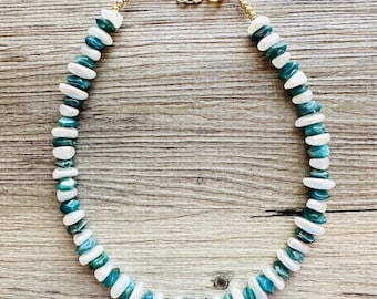 May include: A necklace made of blue and white gemstone beads with a gold chain clasp.