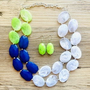 May include: A multi-strand necklace with large oval-shaped beads in shades of white, blue, and green. Matching earrings with green oval-shaped beads.
