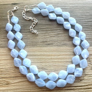 May include: A double-strand necklace made of light blue, faceted, square-shaped beads. The necklace is made with a silver chain and clasp.