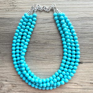 May include: A turquoise blue multi-strand beaded necklace with a silver clasp.