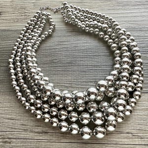 May include: A silver necklace with multiple strands of large, round beads.