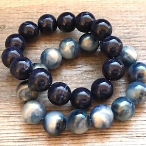 May include: Two bracelets made of blue and white beads. The bracelets are made of round beads and are stacked on top of each other.