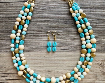 May include: A multi-strand necklace with blue, white, and gold beads. The necklace is paired with matching earrings.