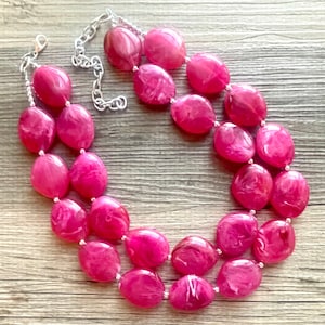 Op de afbeelding: Een dubbele roze ketting met grote, ovale kralen. De kralen hebben een marmer effect met witte swirls.