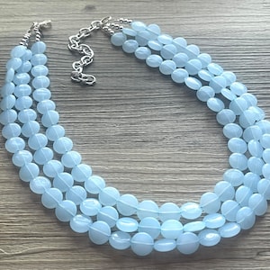 May include: A light blue multi-strand necklace made of round beads. The necklace has a silver clasp.