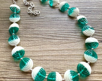 Op de afbeelding: Een witte en tealblauwe ketting met een zilveren ketting. De ketting is gemaakt van ronde kralen met een draaiende print.