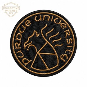 May include: A circular embroidered patch featuring a black background with gold-coloured thread. The text "PURDUE UNIVERSITY" is stitched in a circular pattern around a central graphic of a stylised griffin and a shield emblem.