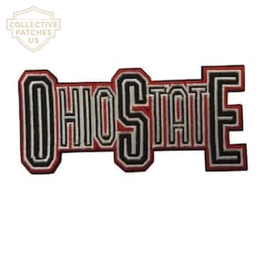 Peut inclure: Un écusson brodé affichant le texte OHIO STATE dans une police en bloc. Les lettres sont soulignées de fil noir, blanc et rouge, créant un effet superposé. L'écusson a une forme rectangulaire distincte avec les lettres reliées en une seule pièce.