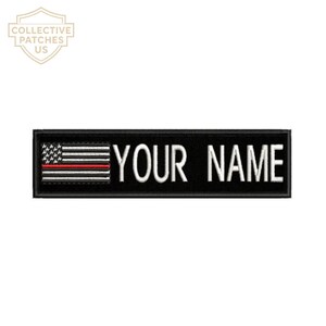 Könnte beinhalten: Ein rechteckiger, schwarz bestickter Aufnäher mit einer stilisierten amerikanischen Flagge auf der linken Seite, die einen horizontalen roten Streifen aufweist. Der Text YOUR NAME ist rechts in weißen Großbuchstaben gestickt.