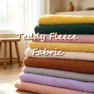 Könnte beinhalten: Ein Stapel gefalteter Teddy-Fleece-Stoff in verschiedenen Farben, darunter Gelb, Dunkelgrün, Rosa, Creme, Braun, Grau, Lavendel und Pfirsich. Der Text "Teddy Fleece Fabric" ist in weißer Schrift über die Mitte des Stapels gelegt.
