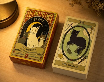 Könnte beinhalten: Ein Cats Rule The Earth Tarot-Kartendeck mit einer Schachtel, die drei Katzen zeigt, und einer Karte namens The World mit einer schwarzen Katze auf einem Globus. Der Text auf der Schachtel lautet 78 Card Deck For The Feline-Obsessed, Thiago Correa und Catherine Davidson.