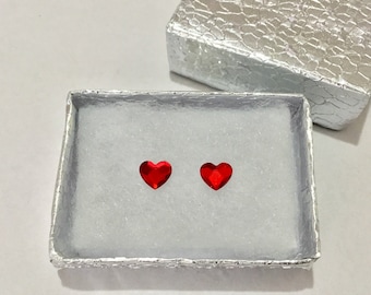 May include: Two red heart-shaped earrings in a silver jewellery box with a textured lid.