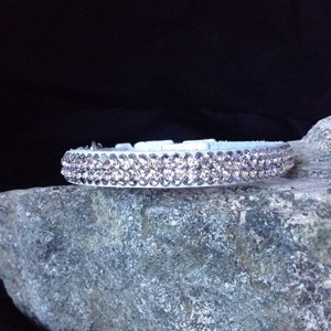 Könnte beinhalten: Ein weißes Lederhundekragen mit zwei Reihen klarer Strasssteine.